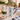 A white ceramic mug with a blue nutcracker and garland design, filled with a hot beverage and topped with cocoa powder, set on a kitchen counter with holiday decor, books, and cookies.