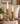 Two brass candlestick holders with lit white taper candles, styled on stacked books in a cozy living room setting.