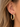 A close-up of a person's ear wearing a polished gold hoop earring.