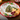 A scalloped ceramic Christmas-themed serving platter with a red rim, decorated with a central Christmas tree, holly, stars, and gold dots, styled with crackers, cheese, cranberries, and walnuts on a wooden table.