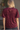 A woman viewed from the back wearing a short-sleeve burgundy velvet top with an allover tonal geometric pattern and a small button closure at the neckline.