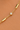 A close-up of a delicate gold chain bracelet with polished rectangular bar links and a central round bezel-set clear stone, shown worn on skin.