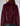 A close-up back view of a model wearing a short, plush faux-fur jacket in deep burgundy against a light gray studio background.