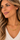A close-up of a woman wearing a gold chain necklace with interlocking oval links, styled with a white knit V-neck top.