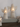 Two white angel-shaped candle holders with wings and small lit candles, displayed on a gray book with the tex on a wooden surface.