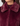 Close-up of a person wearing a plush faux-fur jacket in deep burgundy with a matching collar and a dark ribbed knit top underneath.