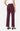 A model shown from the back wearing high-waisted, wide-leg trousers in a deep burgundy color, paired with a white top and black strappy heels, against a plain white studio background.