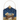 A decorative hanging wall plaque featuring a nativity scene with a baby in a wooden manger under a dark blue starry sky, with a gold star ornament at the top and a gold hanging loop.