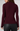 A woman shown from the back wearing a ribbed long-sleeve mock neck sweater in deep burgundy, paired with black leather-look pants, against a light gray studio background.