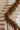 A festive Christmas stair garland with green pine and cedar branches, red berries, and small hanging ornaments draped over a white staircase.