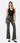 model wearing olive green floral jeans with black tank top on white background
