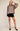 A woman modeling a mocha satin blouse with balloon sleeves and a button-down front, paired with black shorts and black high heels, against a plain beige studio background.