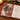 An open decorative notebook on a wooden table, featuring a winter horse illustration on the cover and lined paper inside with the phrase 'Big dreams brighter days and a grateful heart heart'. A lit candle, evergreen branches, and red berries are visible around it.