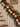 A festive Christmas garland draped over a wooden staircase railing, featuring green pine branches, red and white pom-pom beads, and white beads with red peppermint candy designs.