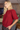 A blonde woman wearing a textured red short-sleeve top with puff sleeves, standing in a cozy indoor setting.