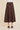A dark brown tiered A-line midi skirt worn with a white top and dark brown slide sandals, shown against a solid beige background.