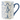A white ceramic mug with a blue handle and rim, decorated with a blue nutcracker, stars, and leafy garlands.