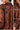 A close-up collage of a women's long-sleeve button-up shirt with a dark navy blue and rust-brown floral pattern. The left panel shows the back view with pleats, while the right panels show detail shots of the collar, pocket, and buttoned cuff.