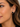 Close-up of a woman's ear wearing a small black cushion-cut stud earring with a polished silver-tone setting.