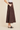 A model wearing a dark brown tiered faux-suede midi skirt with side pockets, paired with a white top and black mule sandals, against a solid beige background.