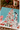 A Christmas-themed jigsaw puzzle featuring a decorated Christmas tree, a Dalmatian dog, a pink pig, and holiday gifts on a snowy blue background, styled on a wooden table with a mug and evergreen branches.
