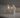 Two white angel-shaped candle holders with small flame-like lights inside, displayed on a white surface against a soft gray background.