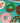A close-up of a jigsaw puzzle showing decorated donut designs on a turquoise puzzle background. Visible donut patterns include green with red dots and a red bow, white with red stripes, and green with red and white decorations.
