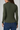 A woman shown from the back wearing a fitted long-sleeve ribbed knit top in olive green, paired with blue jeans, against a plain light gray studio background.