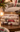 Three stacked decorative books with rustic Christmas illustrations, including a nutcracker and snowman designs, displayed on a wooden table in a cozy holiday setting.