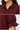 A close-up of a woman wearing a burgundy blouse with a pointed collar, button placket, and gathered puff sleeves with ruffled cuffs, shown in a two-panel detail view.