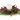 A festive holiday centerpiece featuring a white pillar candle nestled in a wreath of green pine branches and red berries, isolated on a white background.